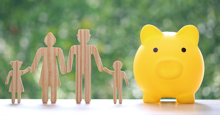 image of a wood figurine family and a yellow piggy bank sitting on a table